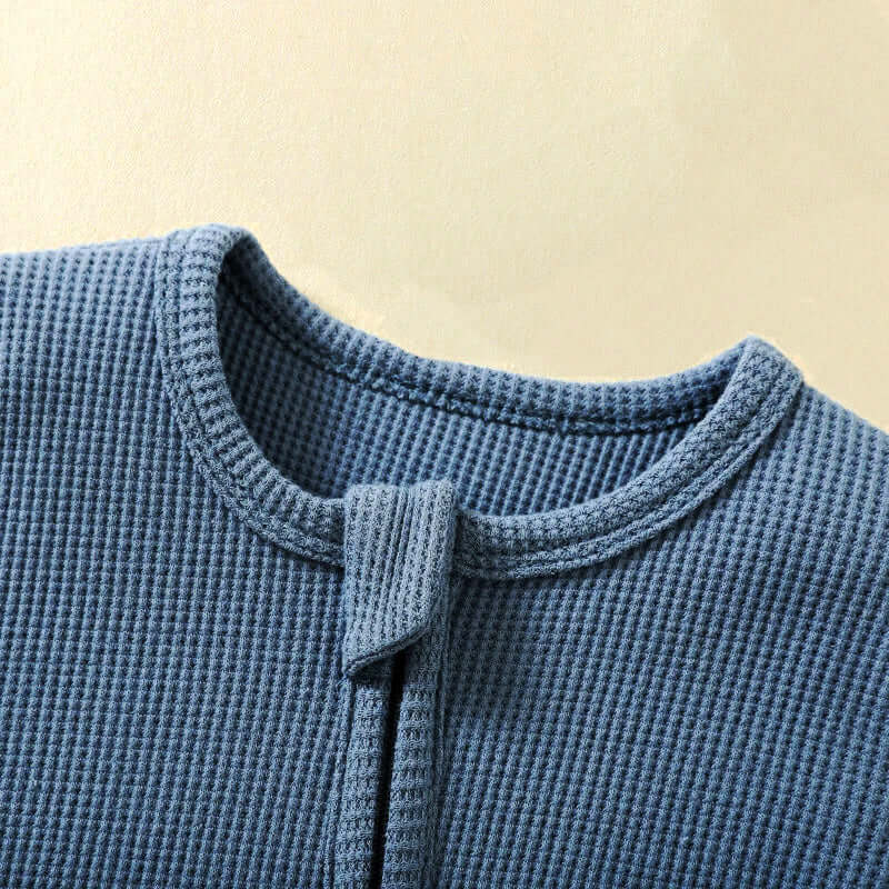 Close-up of 100% organic cotton baby romper in pastel blue with waffle fabric and zipper closure for easy diaper changes.