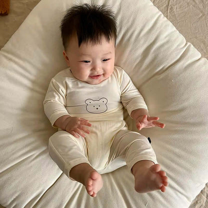 Baby wearing Snuggle Bear Pajamas – Soft & Stretchy 2-Piece Set, smiling on a cozy pillow.