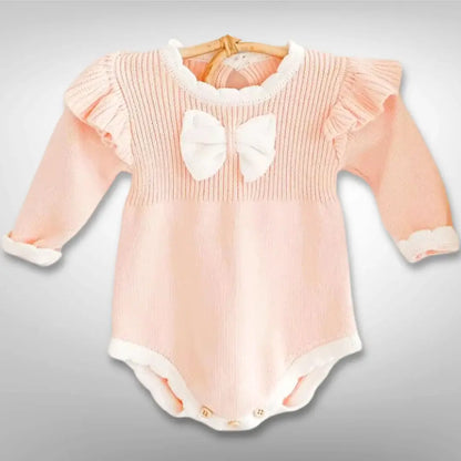 Ballerina Dreams Knit Romper in blush with ruffles and bow, long-sleeved for babies 3-24 months, cozy knit with button closures.