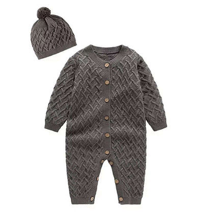 Cozy cable-knit baby romper set with wood buttons and pom-pom beanie in charcoal gray. Warmth and style for little ones 0-24M.