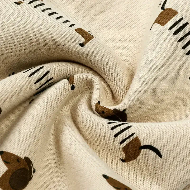 Close-up of fabric featuring playful dachshund print on soft beige material, perfect for a cozy romper.