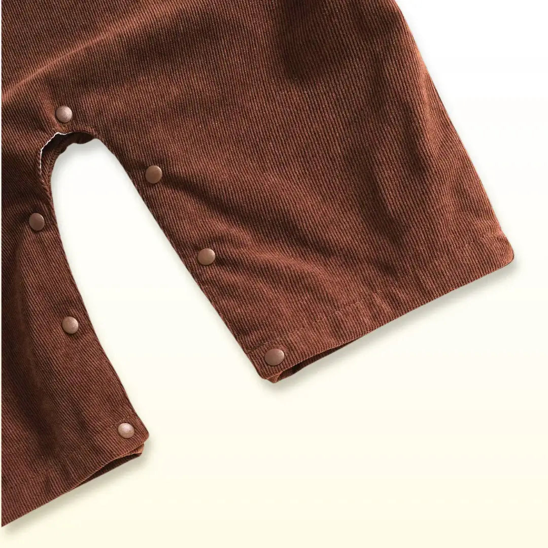 Close-up of brown corduroy fabric and snap closures on baby overalls, perfect for a cozy and practical Thanksgiving outfit.