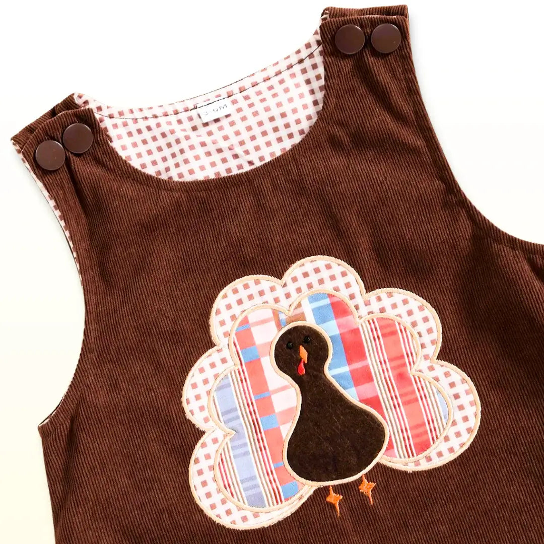 Brown corduroy baby overalls with adorable turkey appliqué, perfect for festive Thanksgiving celebrations and family gatherings.