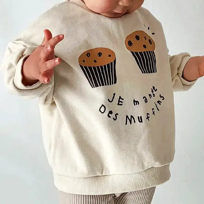 Child wearing "Je Mange Des Muffin" casual sweatshirt with cute muffin design, perfect for ages 18M-6Y, indulging in cozy style.