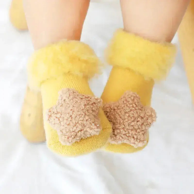 Adorable yellow baby socks with fluffy stars, perfect for keeping tiny feet warm and cozy. Ideal for infants and toddlers.