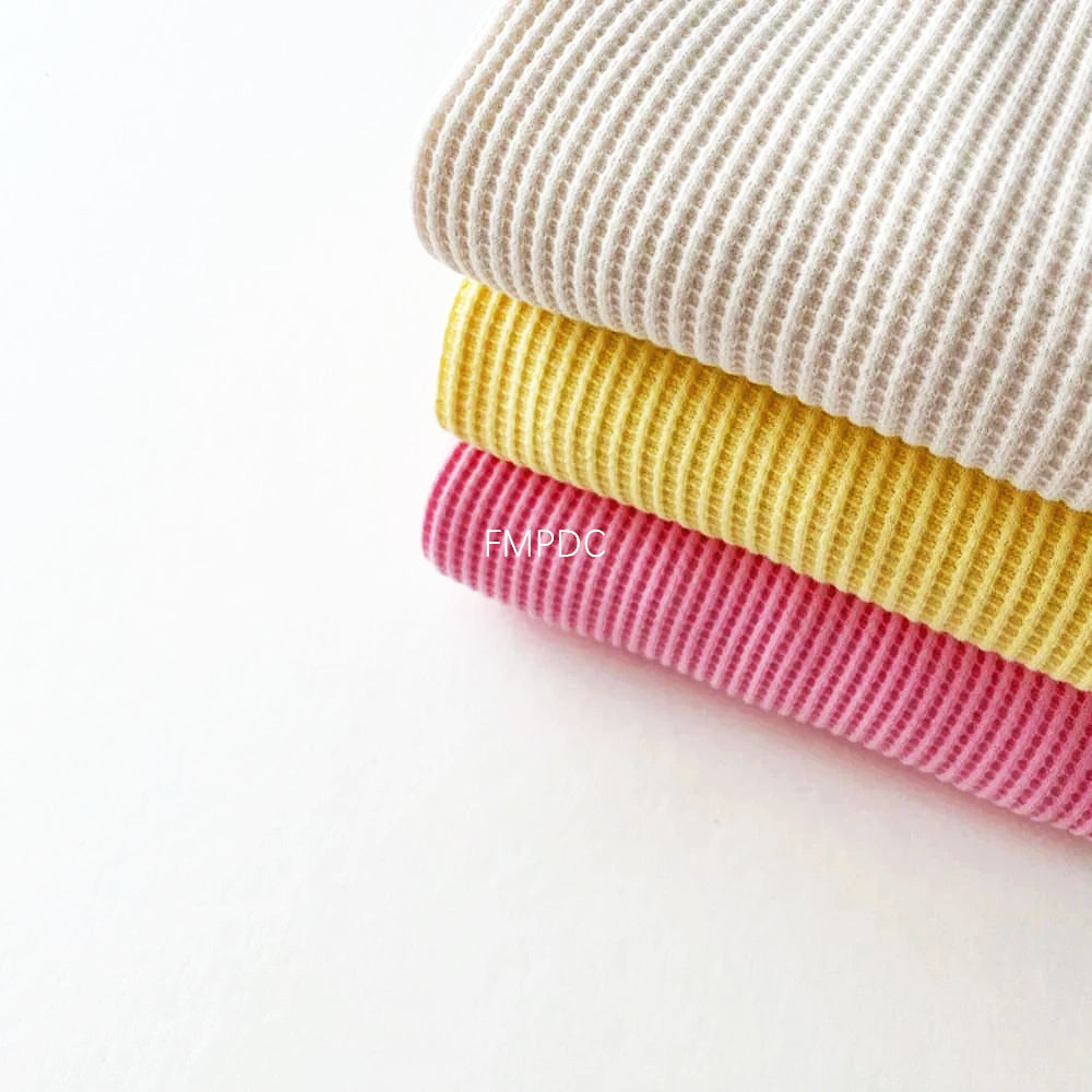 Soft cotton waffle fabric in beige, yellow, and pink, perfect for trendy toddler outfits.