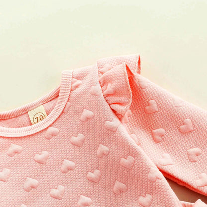 Charming heart prints on infant pink ruffle top with long sleeves.