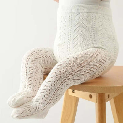 Baby wearing white hollow out mesh tights sitting on a wooden stool, showcasing soft, breathable, and stylish cotton design.