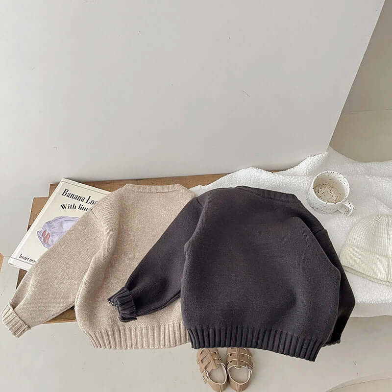 Cozy long-sleeved cotton sweaters in beige and charcoal gray, perfect for keeping your baby warm and casual.